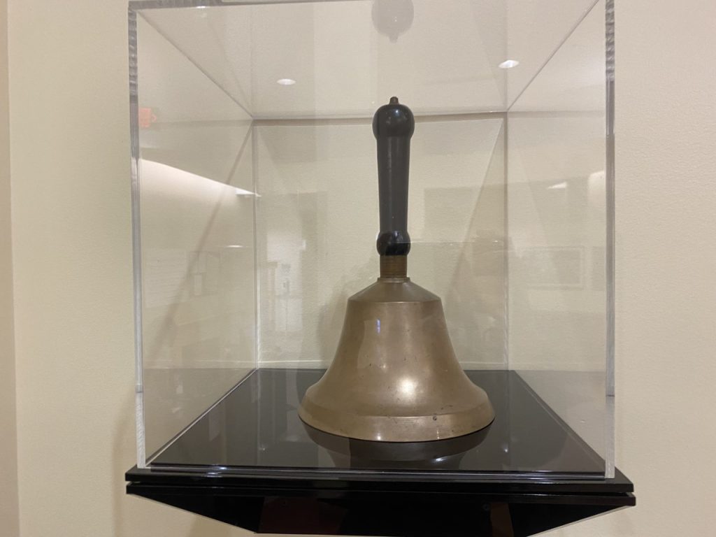 Photo of the original Lyon Park School bell in a glass display case