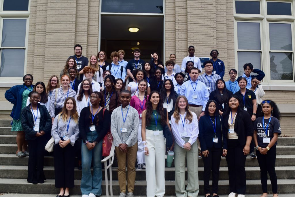 Students visiting Duke University's campus pose outside lecture hall with their CAC advisor