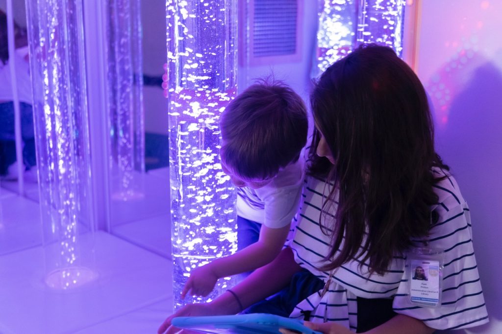 Durham Public Library staff and child read together in the multi sensory environment