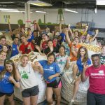 A large crowd of Duke students at the Durham Food bank posing with produce