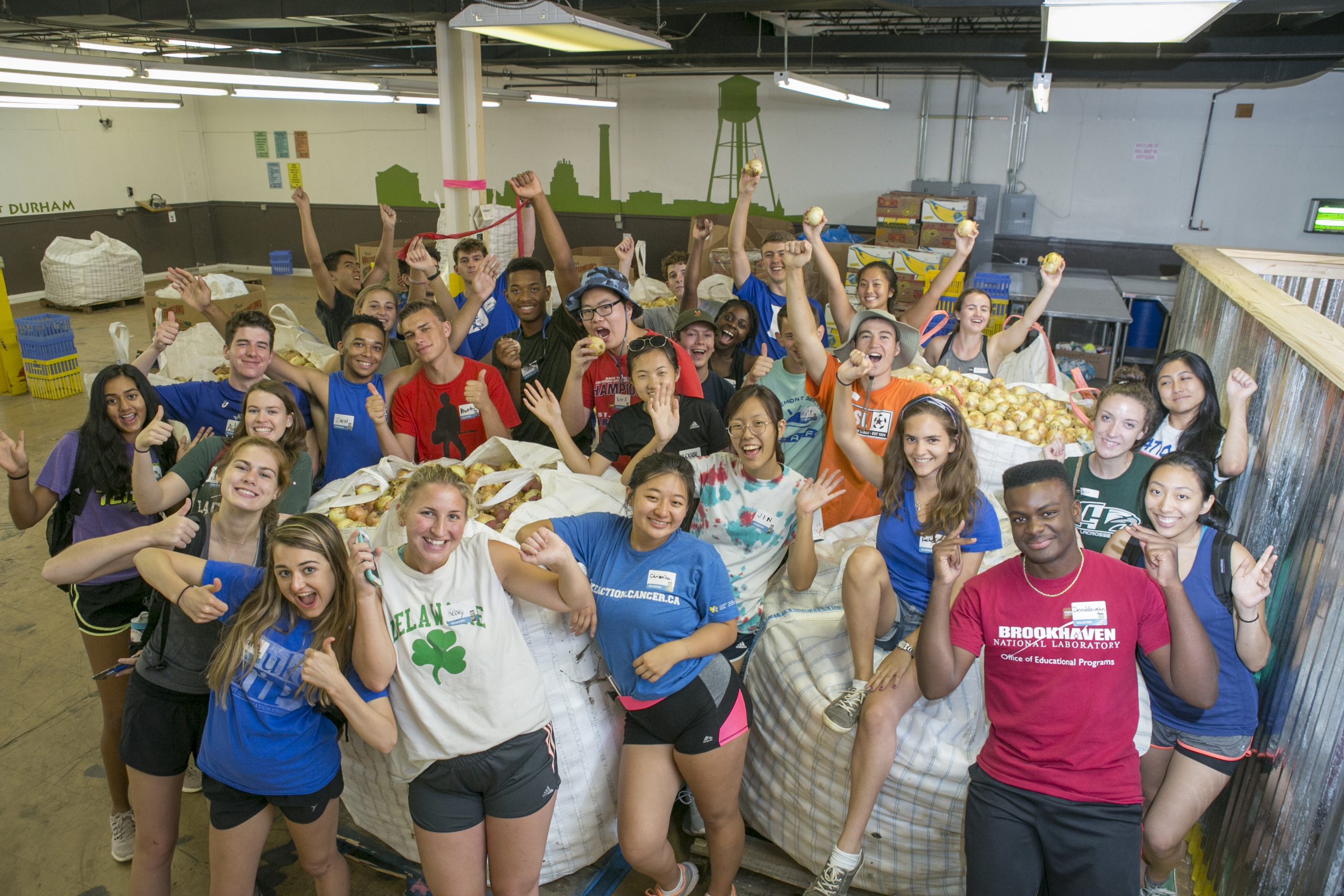 A large crowd of Duke students at the Durham Food bank posing with produce