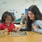 A Duke student tutoring a child while playing checkers