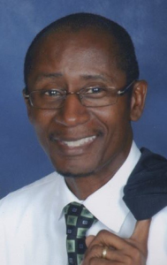 Portrait of Xavier Cason in a dress shirt and tie with jacket over shoulder.